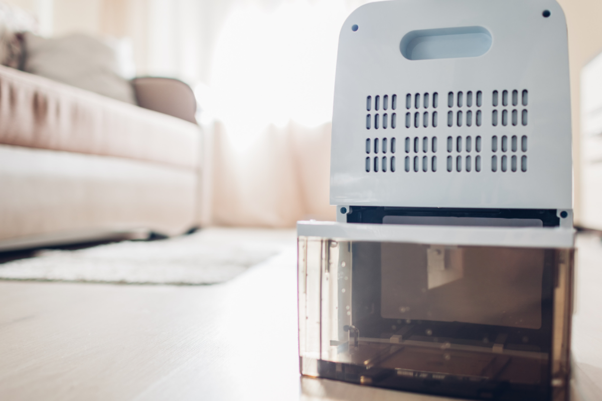 a dehumidifier sitting on the floor in a house with its water reservoir door open.