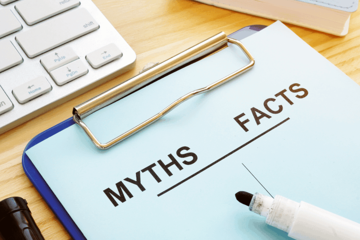 A piece of paper on a clipboard with the word myths on one side and facts on the other side on a desk with a keyboard and pencil nearby