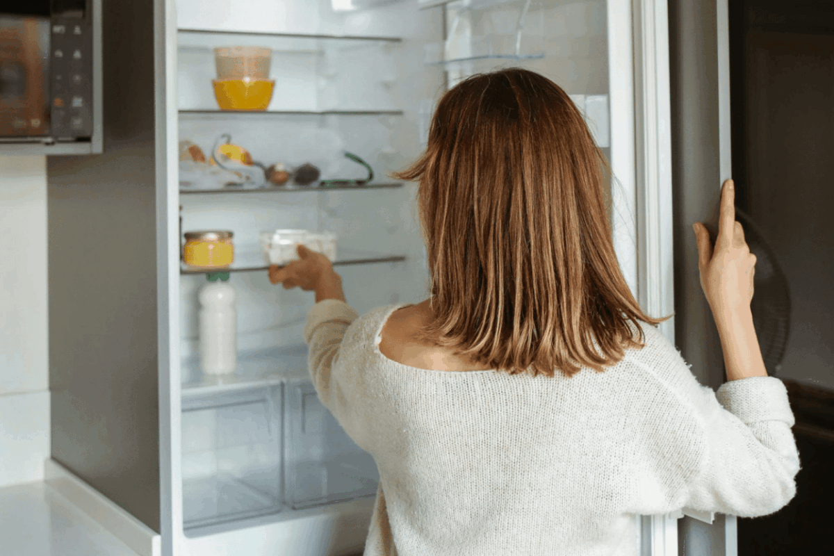 a woman opening an energy efficient refrigerator in a modern kitchen.