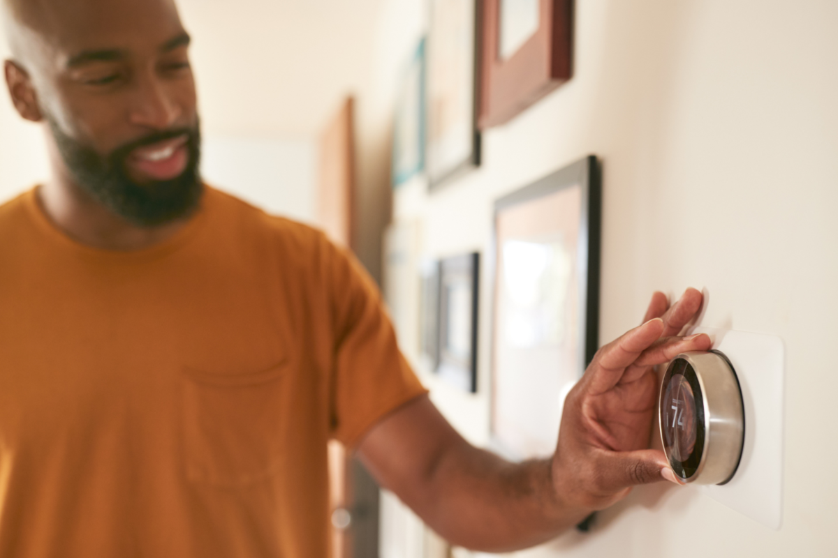 a man adjusting the temperature in his home using a smart thermostat.