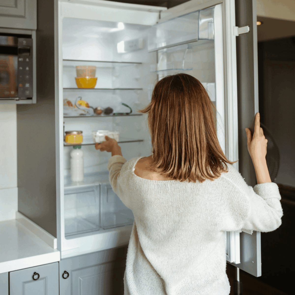 a woman opening an energy efficient refrigerator in a modern kitchen.