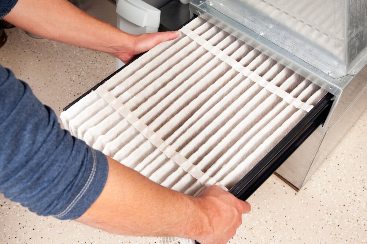 A person checking the filter on their HVAC system.