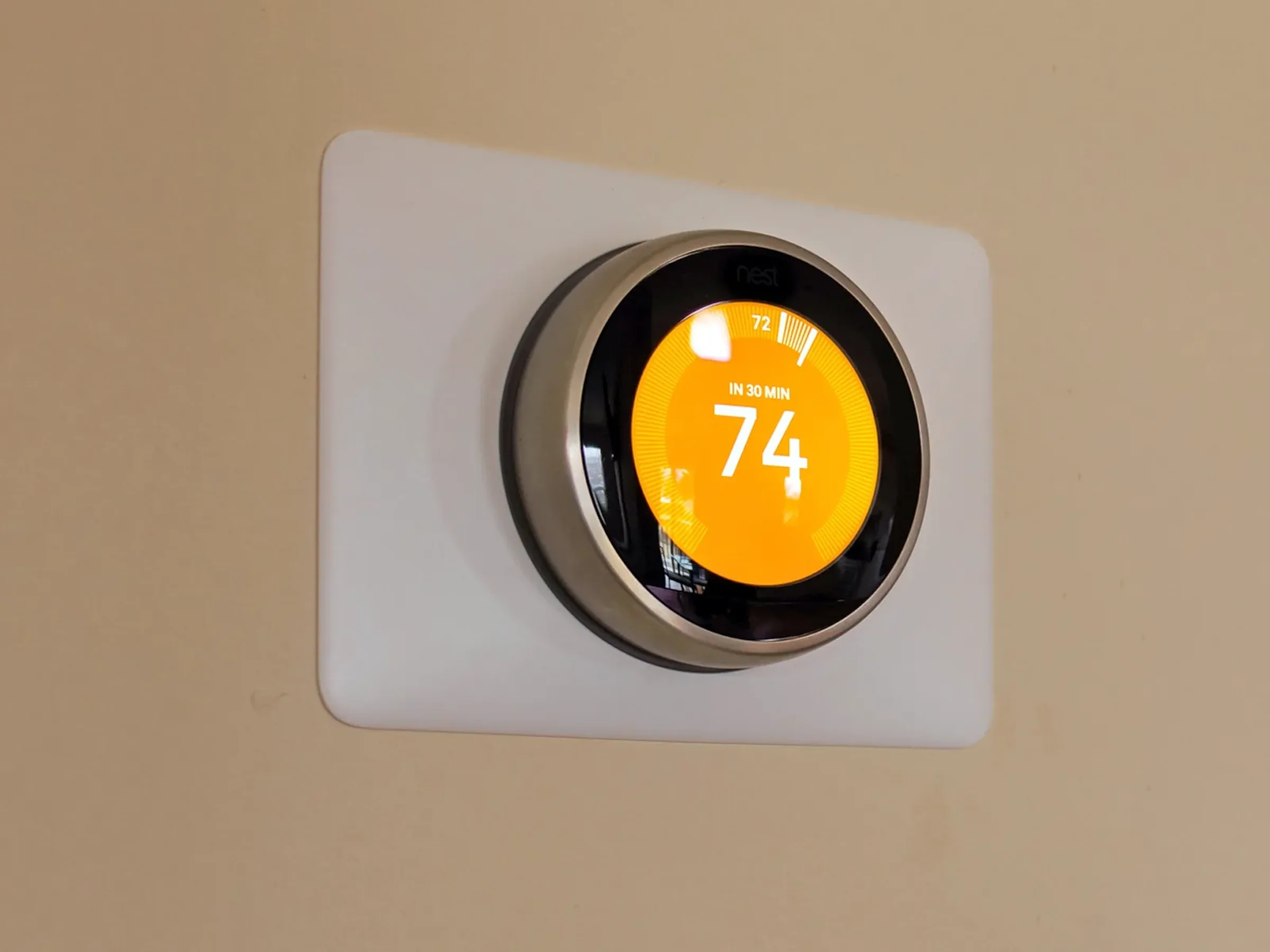 a smart thermostat in a home with its temperature set at 74 degrees Fahrenheit.