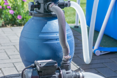 an above-ground pool pump attached to an outdoor pool.