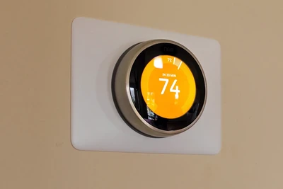 a smart thermostat in a home with its temperature set at 74 degrees Fahrenheit.