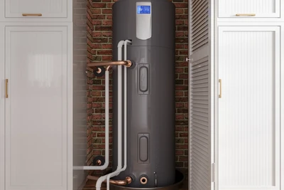 a heat pump water heater installed in-between two cabinets in a home.