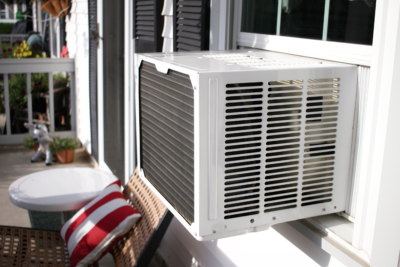 a porch with a window air conditioner unit installed on the house's window.